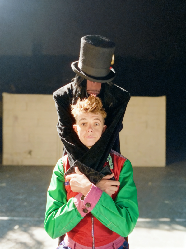 Clown Daddy, AKA Ellie J, in a colorful costume with a top hat character behind them